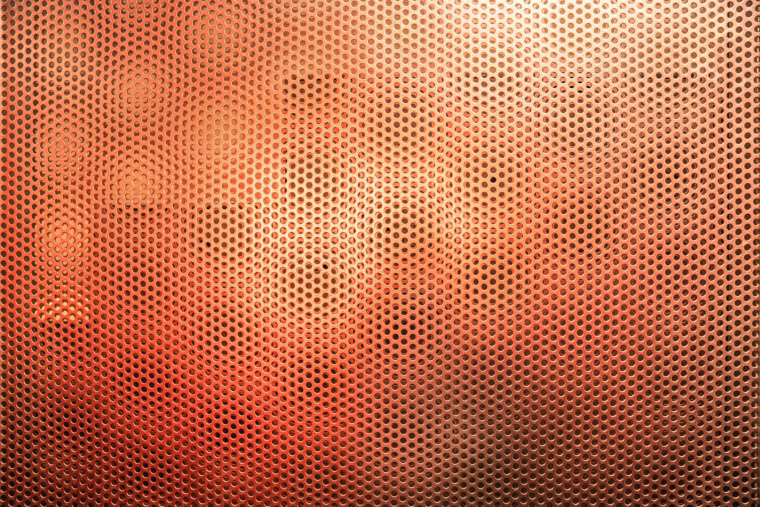 Orangene Wand aus Metal mit Löchern