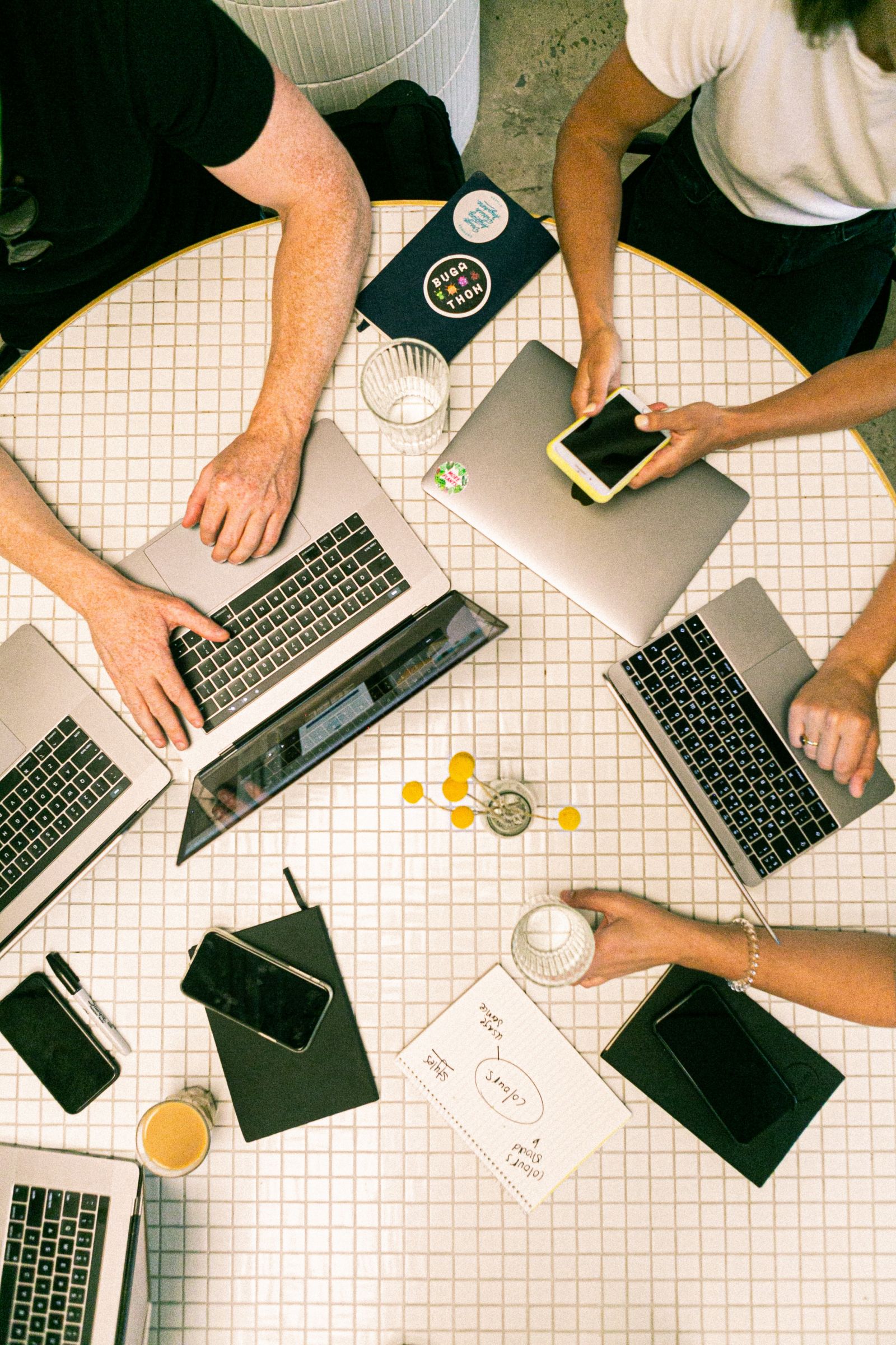 Team sitzt mit Computern um runden Tisch