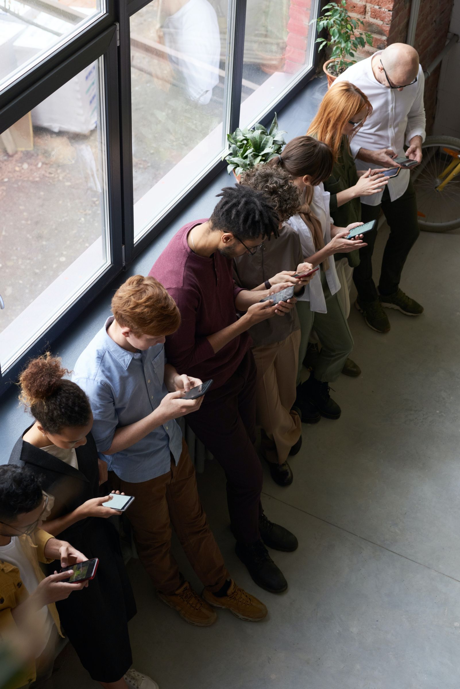 aufs Smartphone guckende Menschen am Fenster