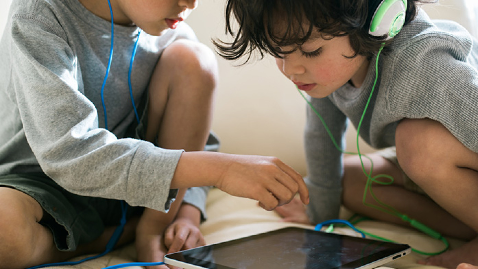 Zwei Kinder mit Kopfhörern und Ipad