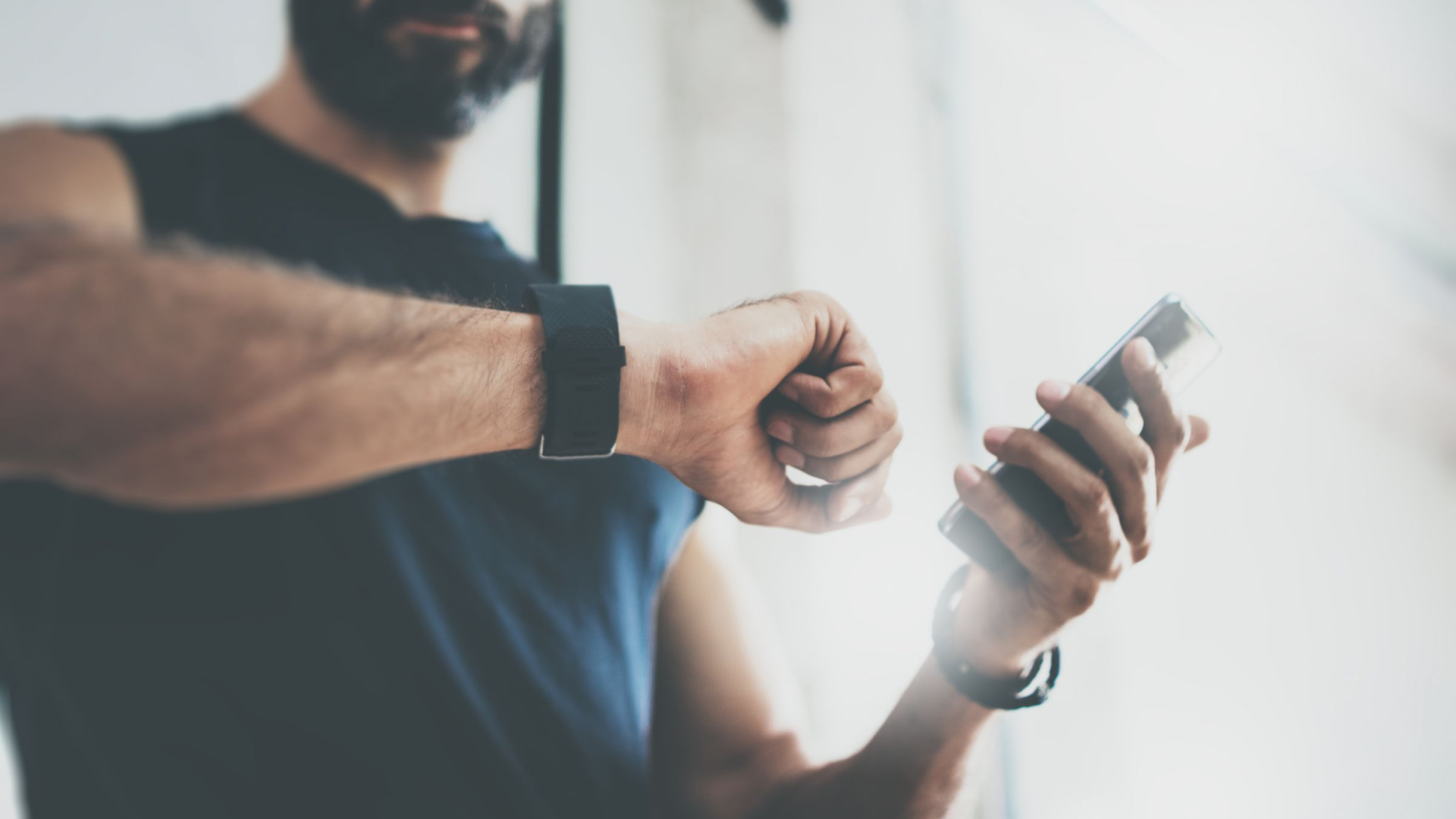 Mann hat Smartphone in der Hand und schaut auf seine Smartwatch