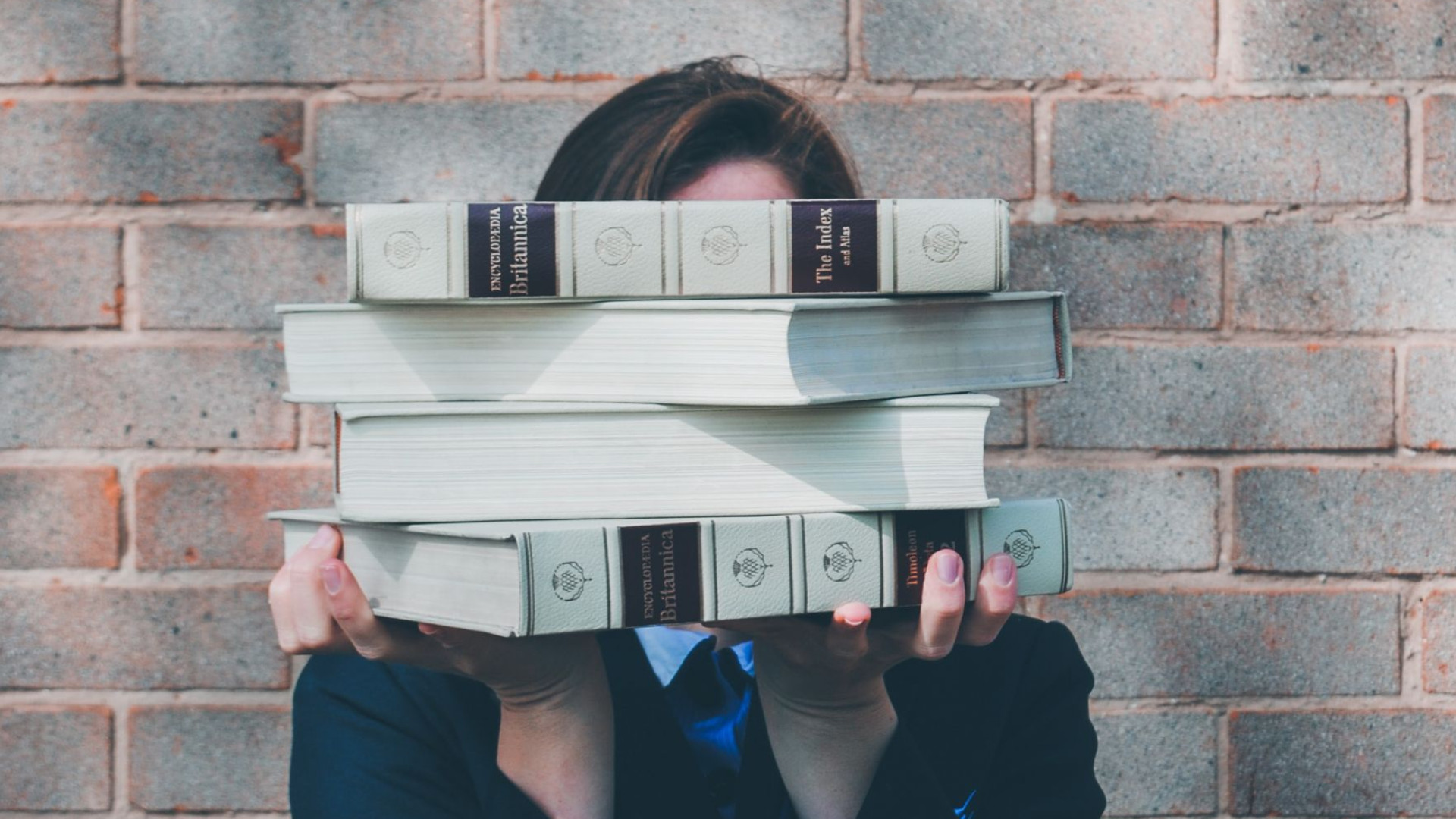 Frau hält Bücher vor ihrem Kopf