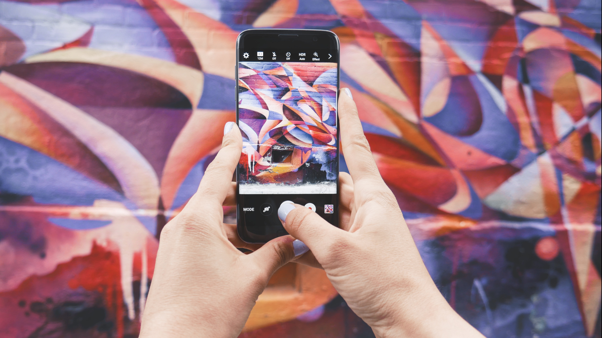 Person fotografiert bunte Wand mit iPhone