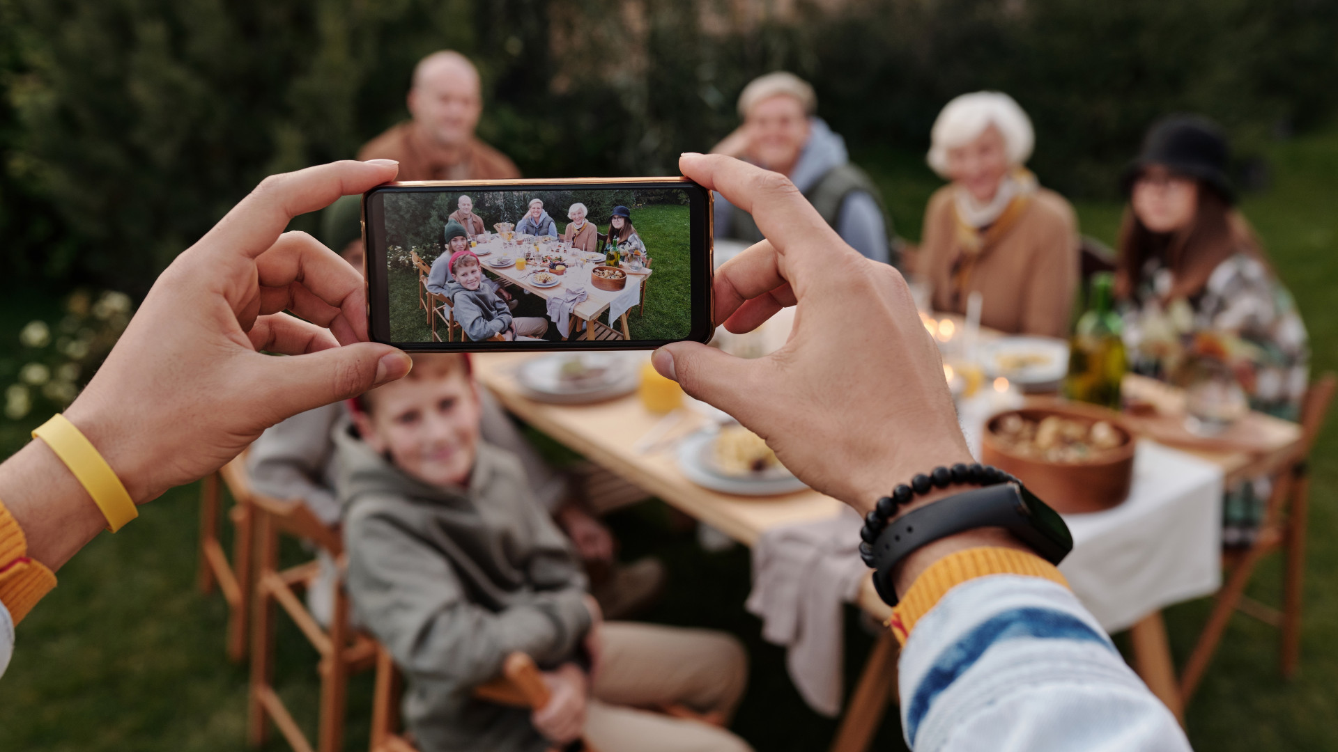 Person fotografiert Familie mit Smartphone