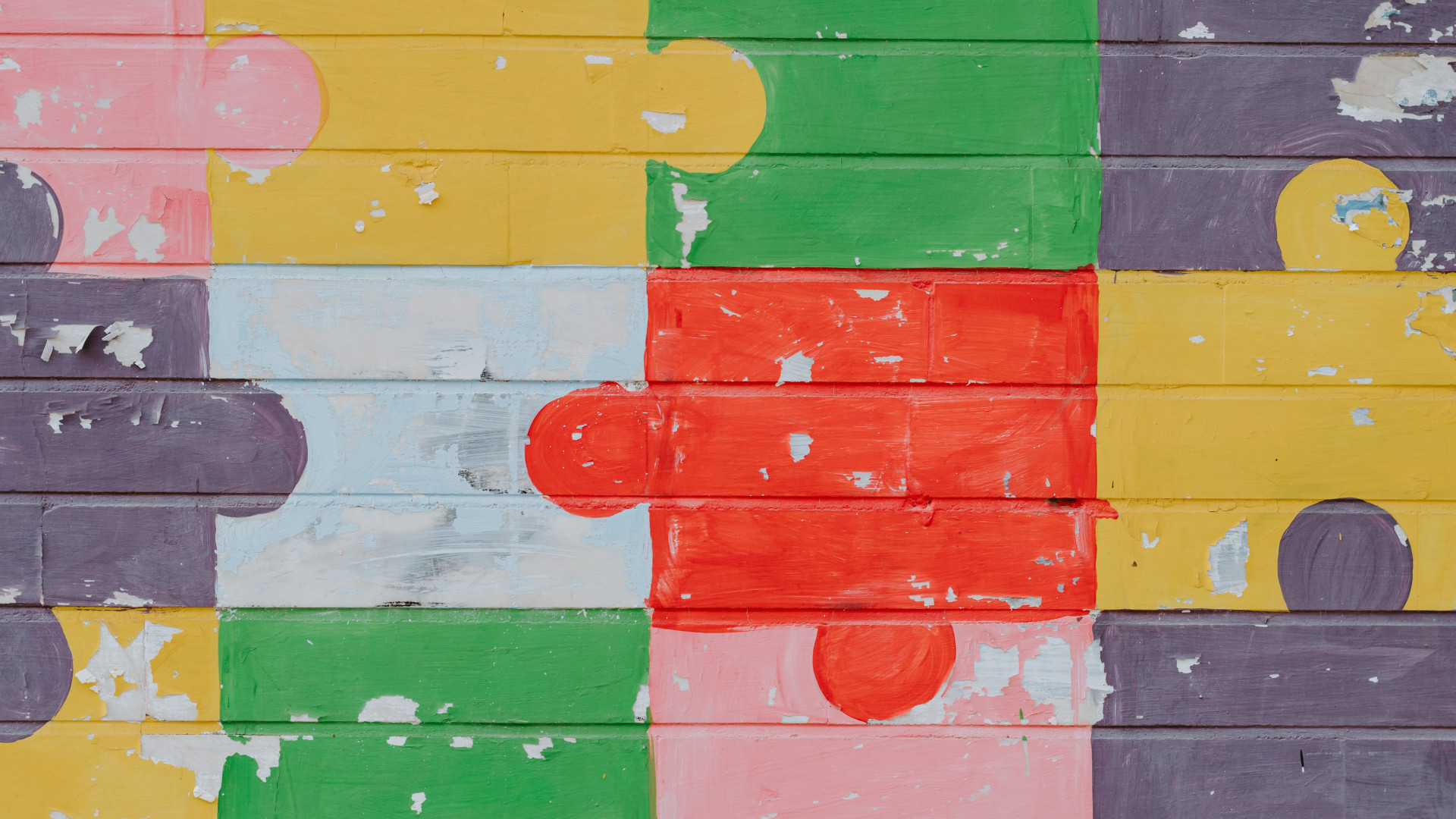 Bunte Puzzleteile auf eine Backsteinmauer gemalt