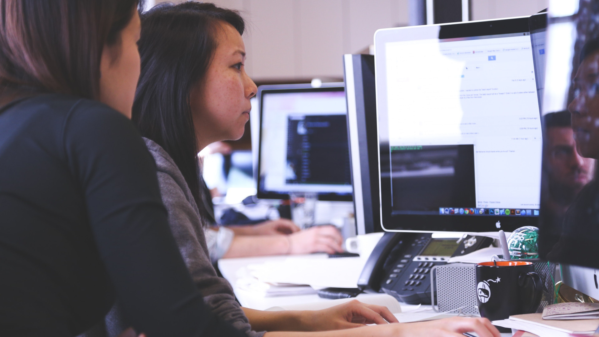 zwei Frauen arbeiten an großen Bildschirmen