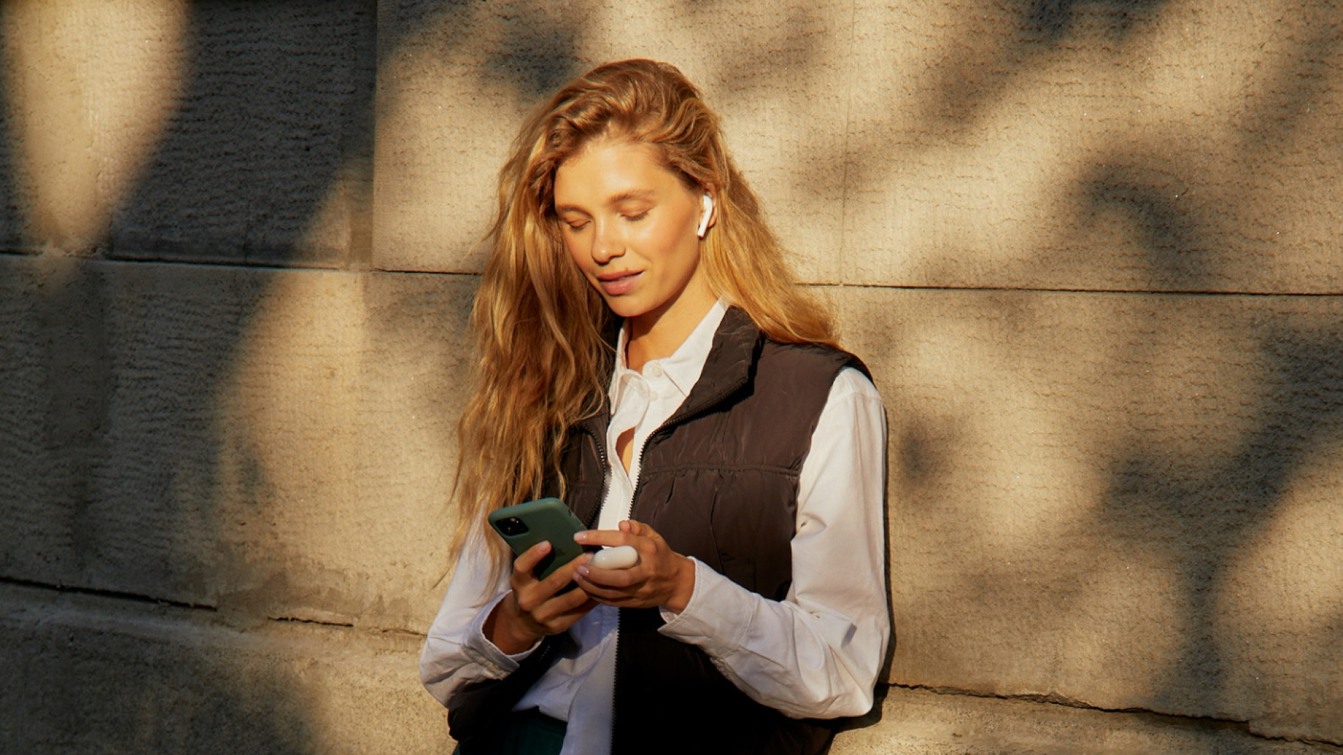Frau mit Kopfhörern guckt auf ihr Handy