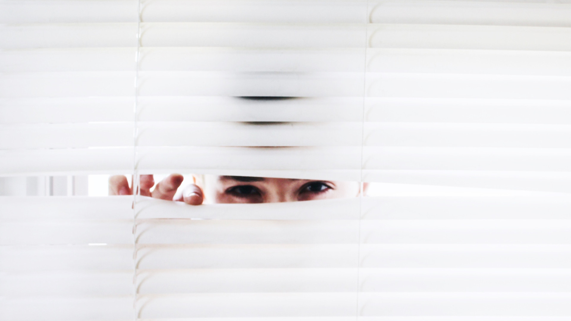 Person guckt durch Rollo