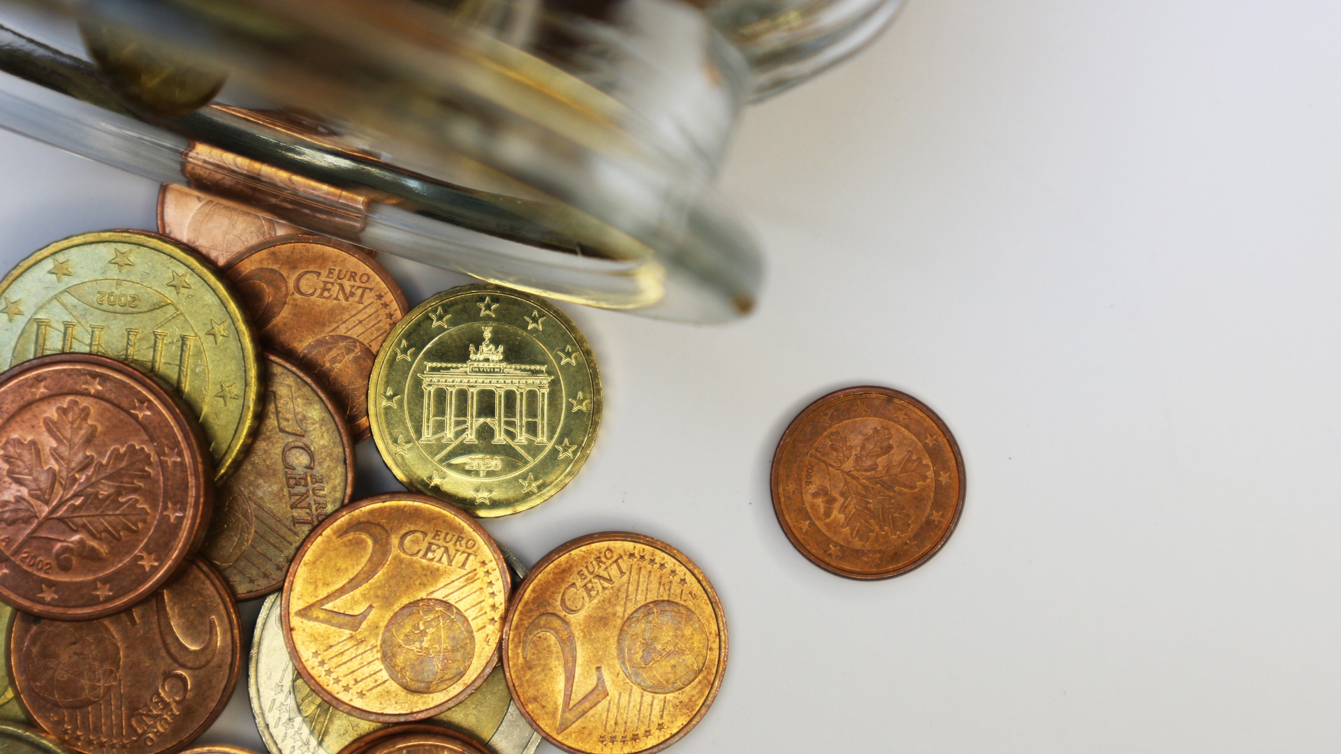 Ausgekipptes Glas mit Geldmünzen