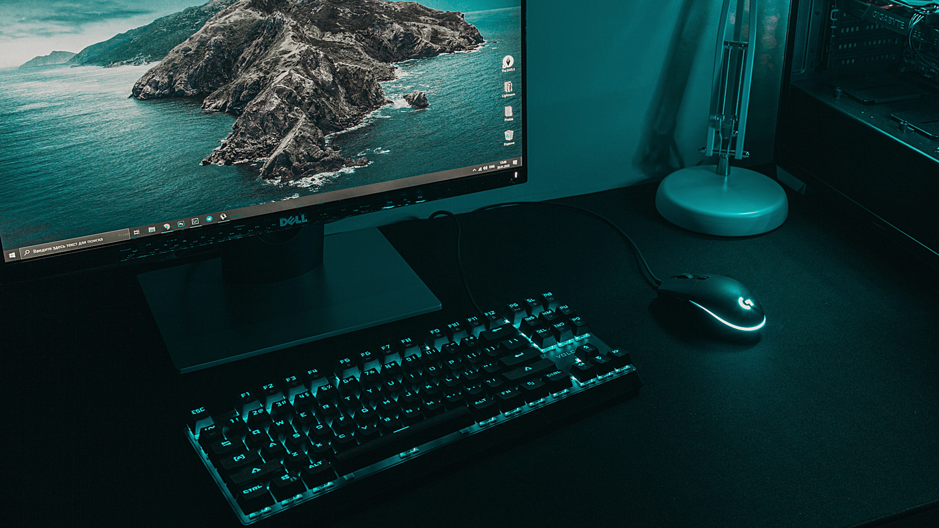 Arbeitsplatz mit DELL-Monitor, beleuchteter Tastatur, Maus und Computergehäuse. Gedämpfte Farben, bläulicher Lichtakzent.