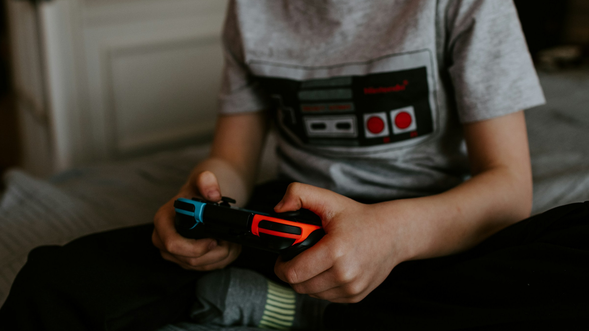 Ein Kind, dass einen Controller in der Hand hält und Videospiele spielt