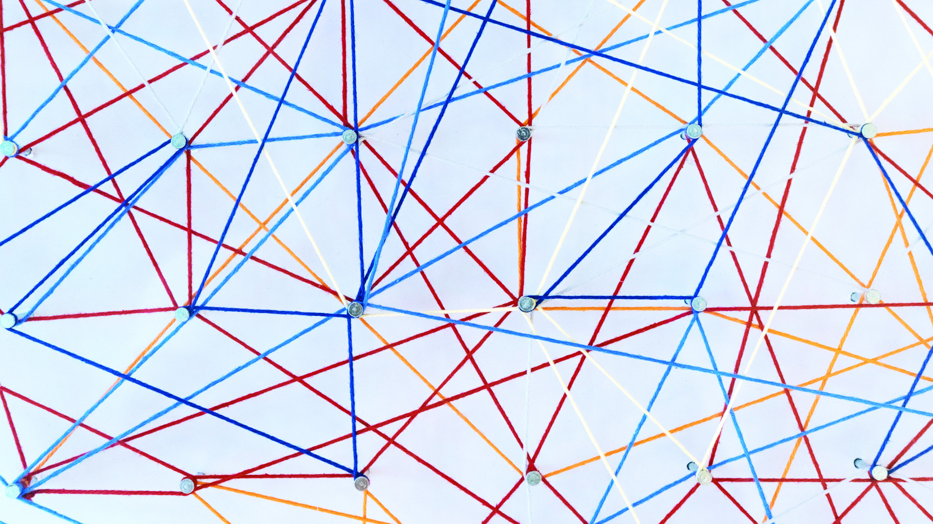 Wand mit Nägeln und bunten Schnüren die wie ein Netz gespannt sind 