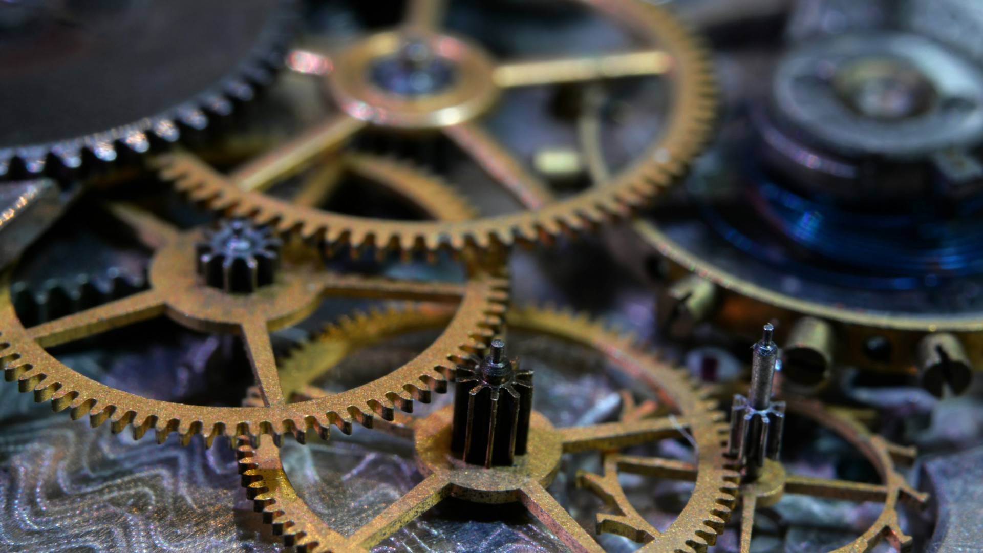 Mehrere ineinandergreifende Zahnräder eines mechanischen Uhrwerks in Nahaufnahme.