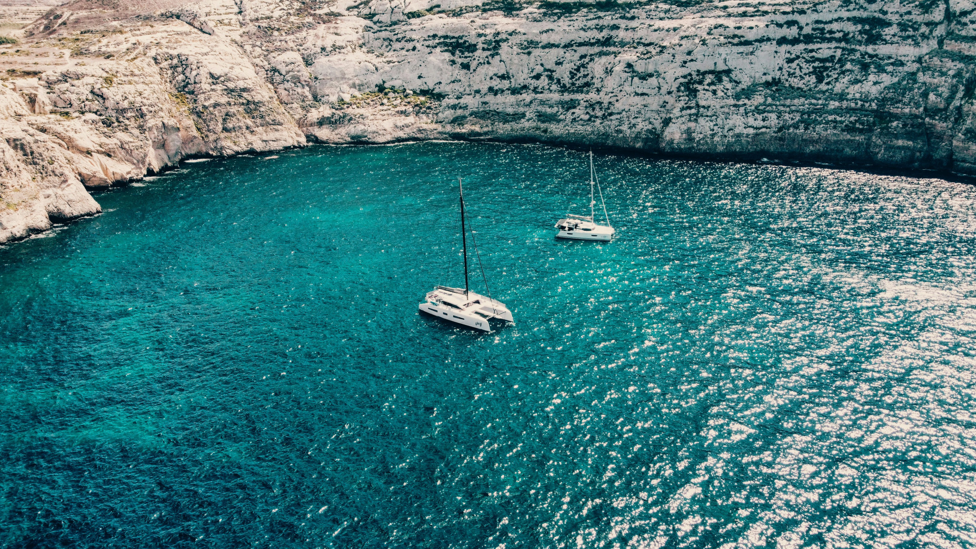 Segelboot in einer Steinbucht auf türkisblauem Wasser 