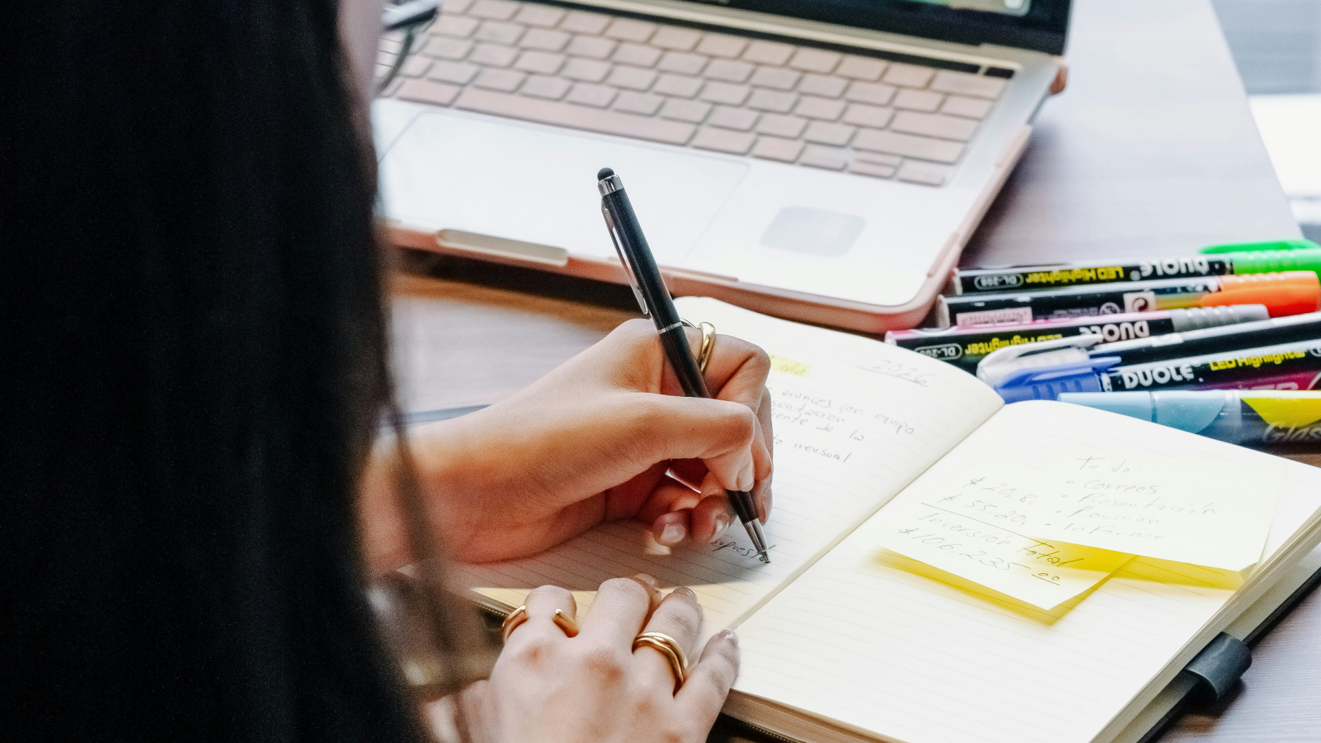 Frau lernt vor Laptop und schreibt in einen Block