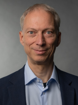 Dr. Thomas Schilling, Person mit grauen Haaren, hellblauem Hemd und dunklem Blazer, neutraler Gesichtsausdruck.