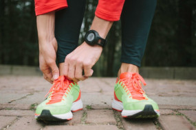 Person mit Laufschuhen und Tracking/Fitness-Armband