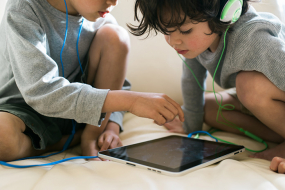 Zwei Kinder mit Kopfhörern und Ipad