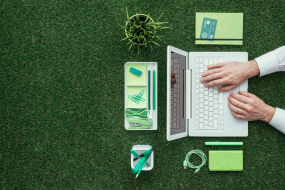 Vogelperspektive auf Laptop und Büroartikel auf Grasoberfläche