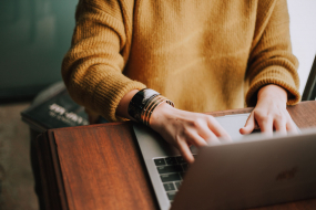 Frau im gelben Pulli am Laptop