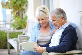 Rentnerpärchen guckt auf Terrasse gemeinsam auf Tablet