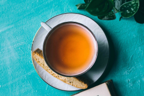 Teetasse auf türkisem Untergrund mit Buch