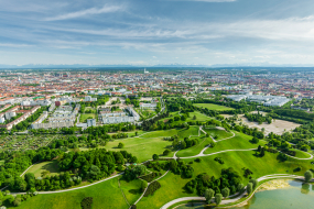 Landschaft mit grüner Wiese und Stadt im Hintergrund