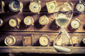 Sanduhr mit Uhren im Hintergrund