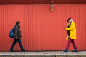 Zwei Personen laufen aufeinander zu, der Senior hält ein Handy in der Hand und schaut darauf