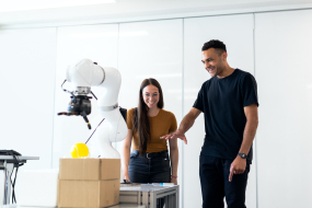 Roboter mit 2 Menschen daneben