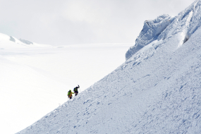 zwei Bergsteiger erklimmen eingschneiten Berg