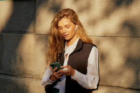 Frau mit Kopfhörern guckt auf ihr Handy