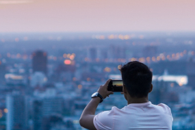 Mann fotografiert die Skyline einer Stadt mit seinem Smartphone.