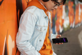 Jugendliche Person mit Smartphone vor Graffiti-Wand