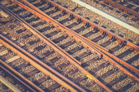 Mehrere rostbraune Eisenbahnschienen auf Holzschwellen im Schotter