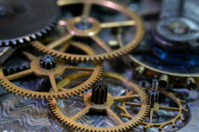 Mehrere ineinandergreifende Zahnräder eines mechanischen Uhrwerks in Nahaufnahme.