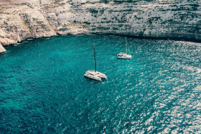 Segelboot in einer Steinbucht auf türkisblauem Wasser 