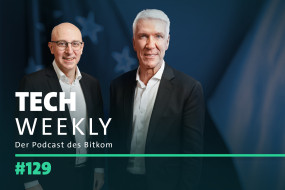 Zwei Männer in formeller Kleidung stehen nebeneinander. Hintergrund mit verschwommenen Flaggen-Elementen. Text: „TECH WEEKLY“, „Der Podcast des Bitkom“, „#129“.