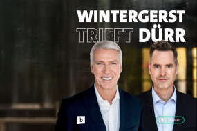 Zwei Männer stehen nebeneinander, lächeln in die Kamera. Text oben: „WINTERGERST TRIFFT DÜRR“. Mikrofon-Symbol unten rechts.