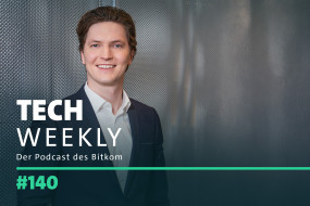 Person in dunklem Anzug und hellem Hemd lächelt vor grauer Wand. Text: "TECH WEEKLY" und "Der Podcast des Bitkom".