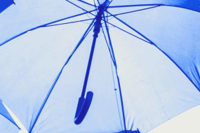 Unterseite eines geöffneten blauen Regenschirms mit sichtbaren Speichen und Schaft.