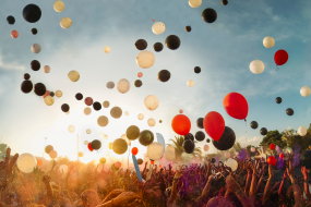 Bunte Luftballons steigen über Menschenmenge in die Luft