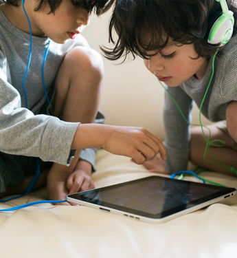 Zwei Kinder mit Kopfhörern und Ipad