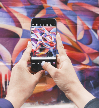 Person fotografiert bunte Wand mit iPhone