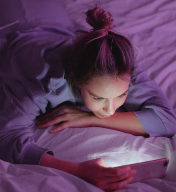 junge Frau mit Smartphone im Bett