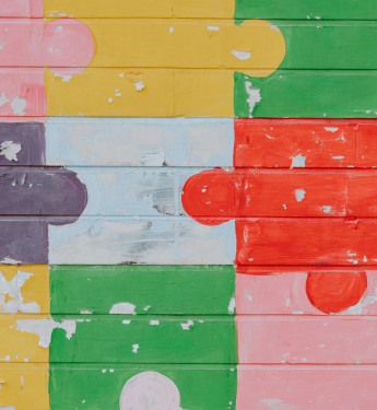 Bunte Puzzleteile auf eine Backsteinmauer gemalt