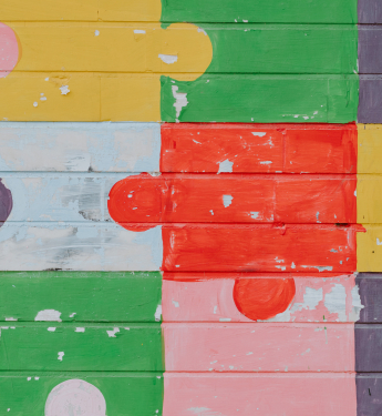 Bunte Puzzleteile auf eine Backsteinmauer gemalt