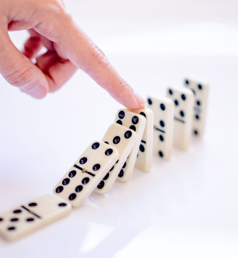 Kippende Dominosteine werden durch einen Finger gestoppt