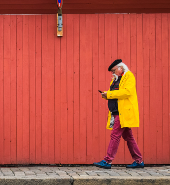 Zwei Personen laufen aufeinander zu, der Senior hält ein Handy in der Hand und schaut darauf