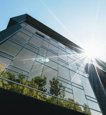 Modernes verglastes Haus in der Sonne mit Baumspiegelung